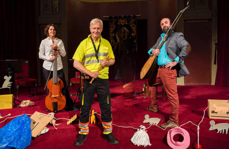 Dos hombres y una mujer sobre un escenario con instrumentos en las manos