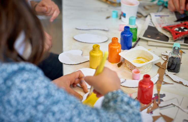 botes de pintura, material de manualidades sobre la mesa, las manos de una niña