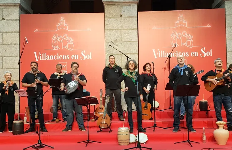 Grupo de gente con instrumentos tradicionales sobre un escenario cantando