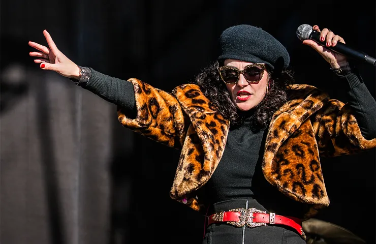 mujer con micrófono en la mano, gafas de sol, boina estilo parisino, torera de animal print