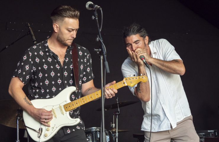 Dos hombres sobre un escenario tocando una guitarra y una armónica