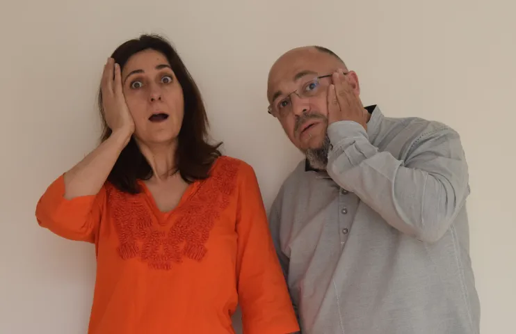 hombre y mujer con una mano en el lateral de la cara y expresión de asombro